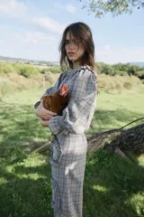 Pantalón de tiro alto con corte recto y diseño de cuadros en tonos grises y naranjas. Presenta detalles de volados aplicados en forma sinuosa a lo largo de las piernas.