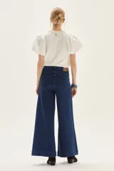 Blusa blanca de calce recto con cuerpo de jersey y mangas cortas tipo globo en popelina. Presenta cuello redondo y detalle de bordado decorativo en la espalda.