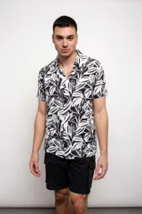 Camisa de manga corta con estampado de hojas en blanco y negro, confeccionada en rayón.