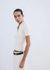 Chaleco de tejido de punto fino y diseño entallado, con cuello camisero, escote en V y mangas cortas.