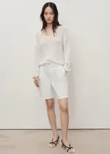 Short de algodón estilo denim, color blanco, de tiro medio con diseño recto, cierre frontal de cremallera y botón, trabillas, bolsillos laterales y traseros, y detalle de pinzas delanteras.