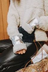 Guantes de cuero metalizado plateado con interior y puños de corderito sintético blanco, diseño sin dedos con manopla rebatible.