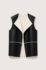 Chaleco de cuero sintético negro con interior de corderito sintético color crema. Diseño sin mangas, con cuello amplio y terminaciones al corte.