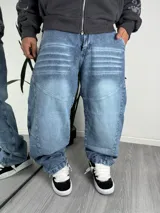 Pantalón jeans estilo baggy de corte holgado, color azul claro con efecto deslavado y detalles de costuras y pliegues horizontales en la parte superior.