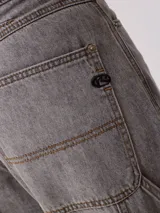 Jean de corte baggy y tiro medio, confeccionado en denim de algodón en tono azul claro con efecto lavado. Presenta diseño de cinco bolsillos, cierre frontal con botón y cremallera, y pernera ancha.