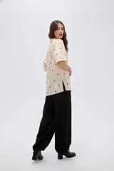 Camisa de lyocell color beige con estampado de lunares negros, cuello solapa, manga corta y cierre frontal con botones.