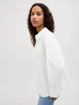 Camisa de popelín blanca de manga larga con cuello clásico y cierre frontal de botones ocultos, de ajuste relajado y puños anchos.