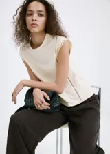 Camiseta sin mangas color beige, con cuello redondo y detalles de encaje en las costuras de los hombros y laterales.