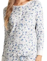 Conjunto de pijama compuesto por una remera de manga larga con escote redondo y cierre frontal de botones, y un pantalón con cintura elástica y lazo de ajuste. Presenta un estampado floral en tonos azules sobre fondo blanco.