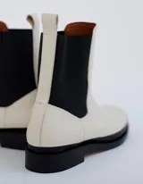 Bota Chelsea color hueso de cuero vacuno, con elástico lateral negro y suela de cuero.