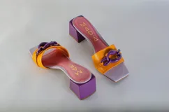 Sandalias tipo sueco color amarillo, con taco ancho y aplique de cadena en el empeine.