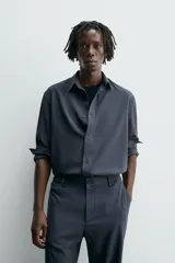 Camisa de corte relajado, color azul marino, con cuello solapa, manga larga con puños abotonados y cierre frontal de botones.