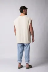 Musculosa oversize de tejido texturado color crema, con cuello redondo y terminaciones deshilachadas en las sisas. Presenta una costura central vertical en la espalda.