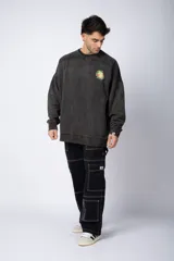 Buzo de cuello redondo y corte oversize, confeccionado en tela friza con efecto de teñido artesanal desgastado. Presenta un estampado pequeño en color verde lima en el pecho y una etiqueta pequeña en el puño.