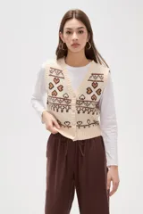 Chaleco tejido de punto con diseño jacquard de corazones y motivos geométricos en tonos verde y rosa. Presenta escote en V, cierre frontal con botones y terminaciones acanaladas en cuello, sisas y ruedo.