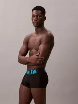 Pack de tres bóxers tipo trunk de Calvin Klein, color negro. La cinturilla elástica distintiva presenta el logo de la marca en tres colores: azul cian, blanco y blanco.