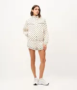 Campera rompeviento deportiva Get Over de microfibra, con estampado de lunares, cuello alto, cierre frontal oculto, bolsillos delanteros con ribete oscuro y puños elásticos.