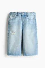 Bermuda de cinco bolsillos en denim de algodón rígido, corte holgado con cierre y botón, lavado claro y detalles de roturas.