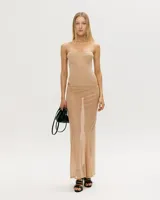 Conjunto de dos piezas en color beige, compuesto por un body estilo corset con copas estructuradas y tirantes finos, y una falda larga de corte recto confeccionada en tejido de malla semitransparente.