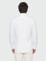 Camisa blanca de manga larga con corte slim fit, confeccionada en jersey elástico de alto rendimiento con sutil estampado. Cuenta con cuello camisero clásico y cierre frontal de botones.