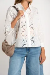 Blusa blanca de manga larga con cuello camisero y bordado tipo broderie anglaise con diseño floral calado.