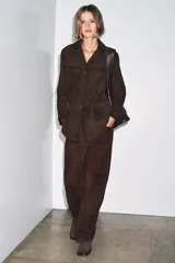 Blazer de mujer color marrón oscuro, confeccionado en piel de ante 100%. Presenta cuello solapa de muescas, manga larga, bolsillos de plastrón frontales y cierre frontal de botones.