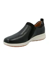 Zapatilla tipo slip-on Hush Puppies modelo Spinal, confeccionada en cuero negro con detalles en gamuza y cierre lateral. Cuenta con una suela de goma blanca con base antideslizante y tecnología de amortiguación.