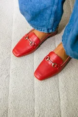 Mocasines de cuero color verde oliva, con detalle de herraje metálico dorado en el empeine y taco bajo cuadrado.