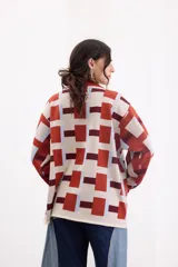 Sweater de tejido de punto con diseño geométrico a cuadros en tonos beige, terracota, bordó y celeste, de corte holgado, manga larga y cuello redondo.