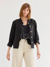 Chaqueta color beige de lino y algodón, con cuello mao, corte recto, bolsillos frontales y cierre con botones de madera.