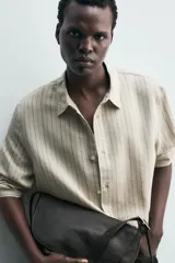 Camisa de corte regular confeccionada en tejido con mezcla de modal, con diseño de rayas verticales, cuello solapa, manga larga con puños abotonados y cierre frontal de botones.