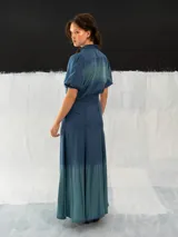 Blusa azul de algodón tipo seda, teñida a mano con técnica tie dye. Tiene corte recto, mangas cortas abullonadas con elástico y cierre invisible en el escote delantero.