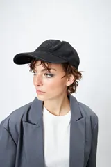 Gorra de algodón negra con diseño clásico tipo baseball y bordado frontal en relieve con la palabra "Brooklyn". Cuenta con visera curva y correa regulable con hebilla metálica en la parte posterior.