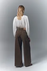 Jean de corte oxford y tiro alto, con pierna ancha desde la cadera hasta el ruedo. Confeccionado en denim rígido de color marrón, con cierre y botón frontal.