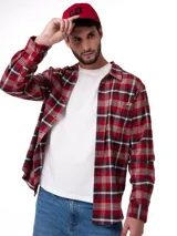 Camisa de manga larga con estampado de cuadros en tonos rojos, negros y blancos. Presenta cuello camisero, cierre frontal con botones, puños abotonados y un bolsillo en el pecho con etiqueta de la marca.