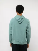 Canguro de felpa color verde menta, con capucha, bolsillo canguro frontal y etiqueta del logo Umbro en la parte delantera.