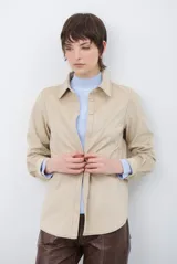 Camisa de estilo casual confeccionada en material tipo gamuza color marrón, con cuello clásico, cierre frontal con botones y costuras a la vista en tono contrastante.