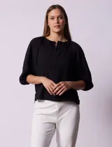 Blusa de gasa blanca con estampado de hojas en azul marino, cuello a la base con escote en V y botones, y mangas cortas abullonadas.