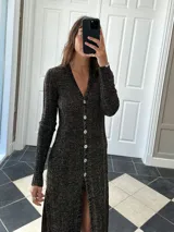 Vestido midi de punto color negro con detalles dorados, escote en V, mangas largas y abertura frontal.