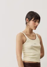 Musculosa de tejido rib color beige con detalles marrones en los bordes del cuello y sisas. Cuenta con el logotipo de la marca bordado en el pecho.