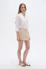 Short pollera color rosa viejo, de diseño cruzado tipo envolvente con detalle de botones laterales.