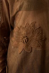 Camisola larga de red marrón, con diseño de tejido a cuadros y apliques florales bordados en relieve por toda la prenda. Presenta cuello camisero y botones frontales.