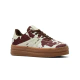 Championes de plataforma con diseño de estampado animal print tipo vaca en tonos marrón y blanco, con cordones marrones y suela de goma color caramelo.