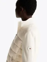 Campera Tommy Hilfiger con cuerpo acolchado de plumón y mangas de punto a contraste. Presenta cuello levantado, cierre frontal de cremallera, puños de punto canalé y dos bolsillos laterales con cremallera.