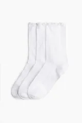 Pack de tres pares de medias blancas de algodón con textura acanalada y borde superior con volados.