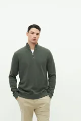 Buzo verde oscuro de felpa con medio cierre frontal, cuello alto y logo de goma en el pecho.