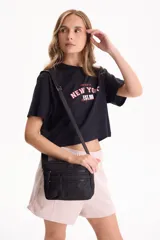 Remera cropped de algodón color negro con diseño gráfico estampado en el frente con las inscripciones 'One day in', 'NEW YORK' y 'EST. 69'. Presenta mangas cortas y calce cómodo.