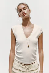 Camiseta color crudo de corte slim fit, con escote en pico, manga corta y tejido de punto acanalado.