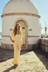 Pantalón de corte holgado con piernas amplias y bolsillos al bies. Modelo de tiro bajo con elástico revestido y cordones para ajustar enlazados a los lados, decorados con cuentas en los extremos.