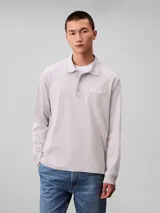 Chomba de manga larga Calvin Klein color gris, confeccionada en tejido jersey grueso aterciopelado de algodón. Cuenta con cuello clásico, cierre frontal con tres botones y logo de la marca bordado en relieve en el pecho.